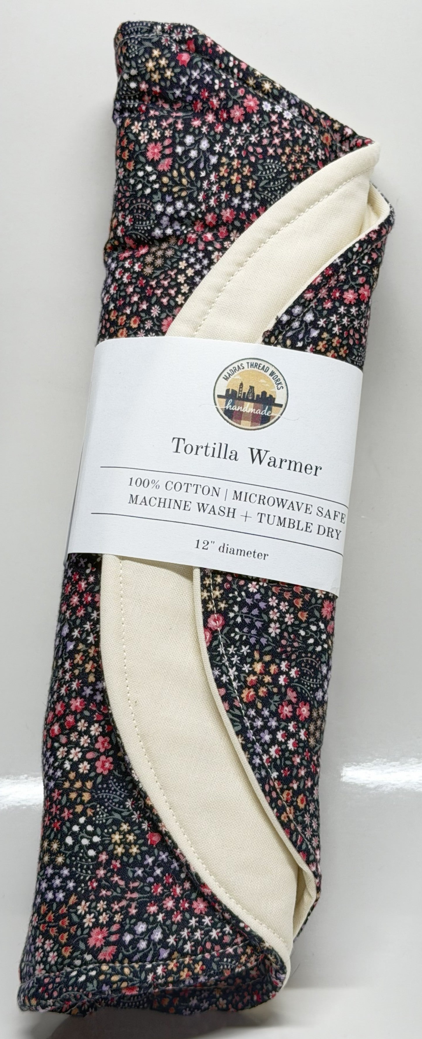 Floral-patterned tortilla warmer with a label on a white background