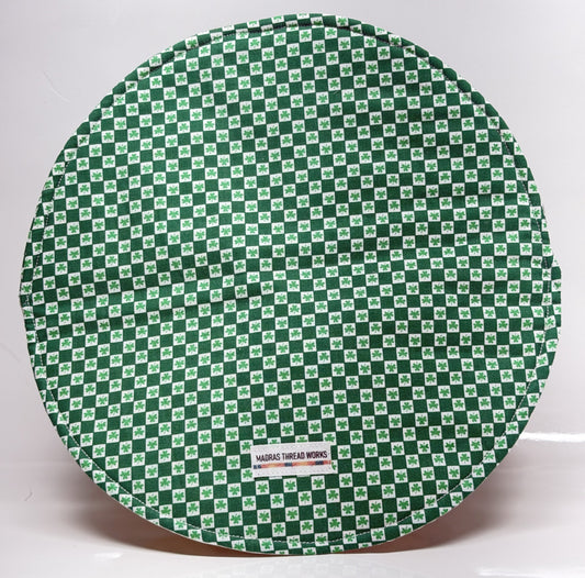 Round green and white checkered mat with a visible brand label on a white background