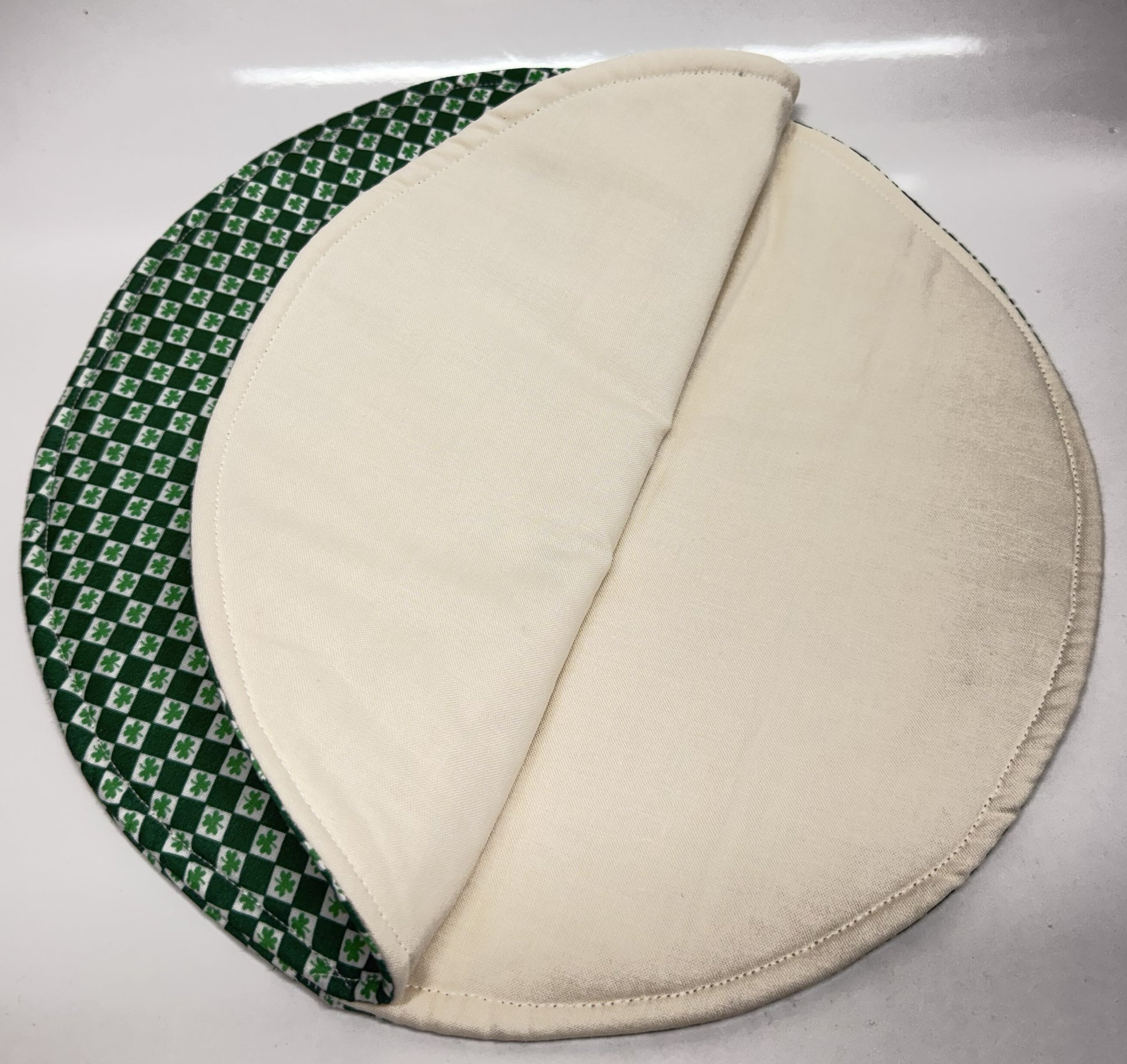 Two circular fabric pads, one green with a pattern and one beige, on a white surface. Inside of the product.