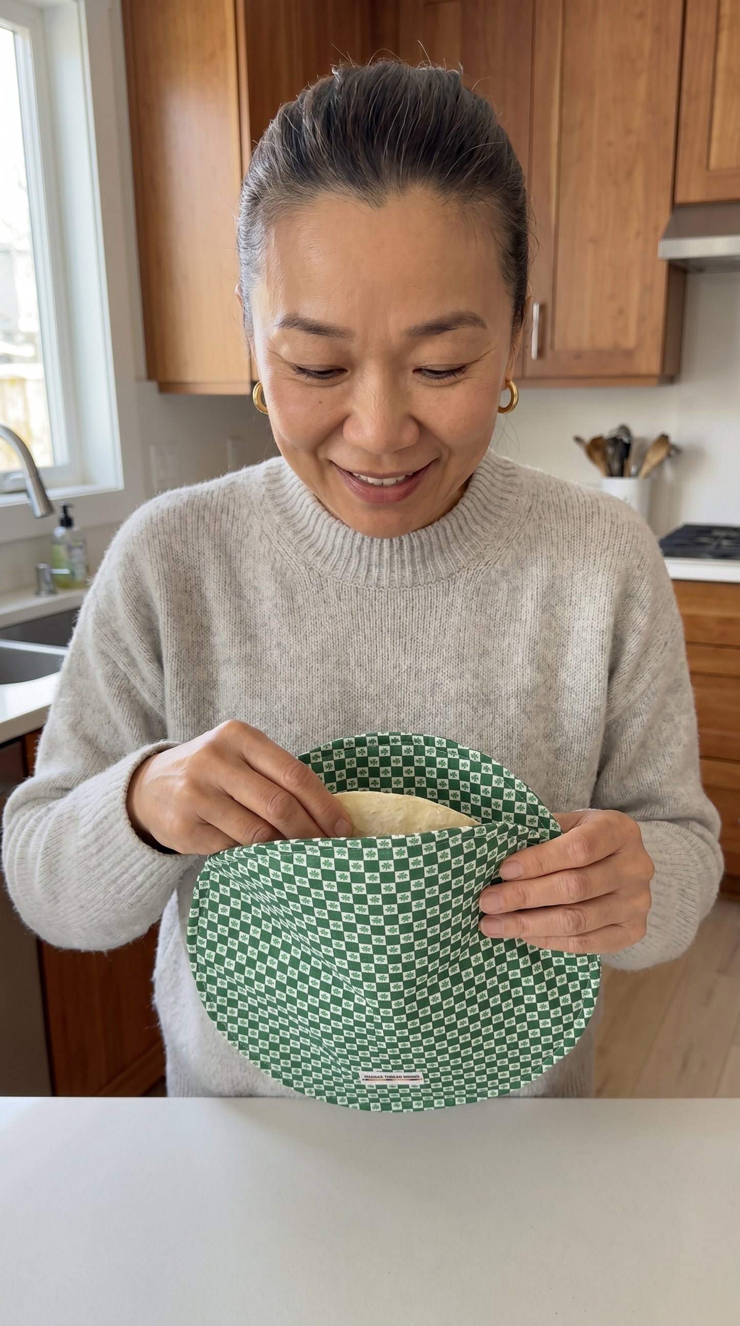 Woman holding a green tortilla warmer in a kitchen